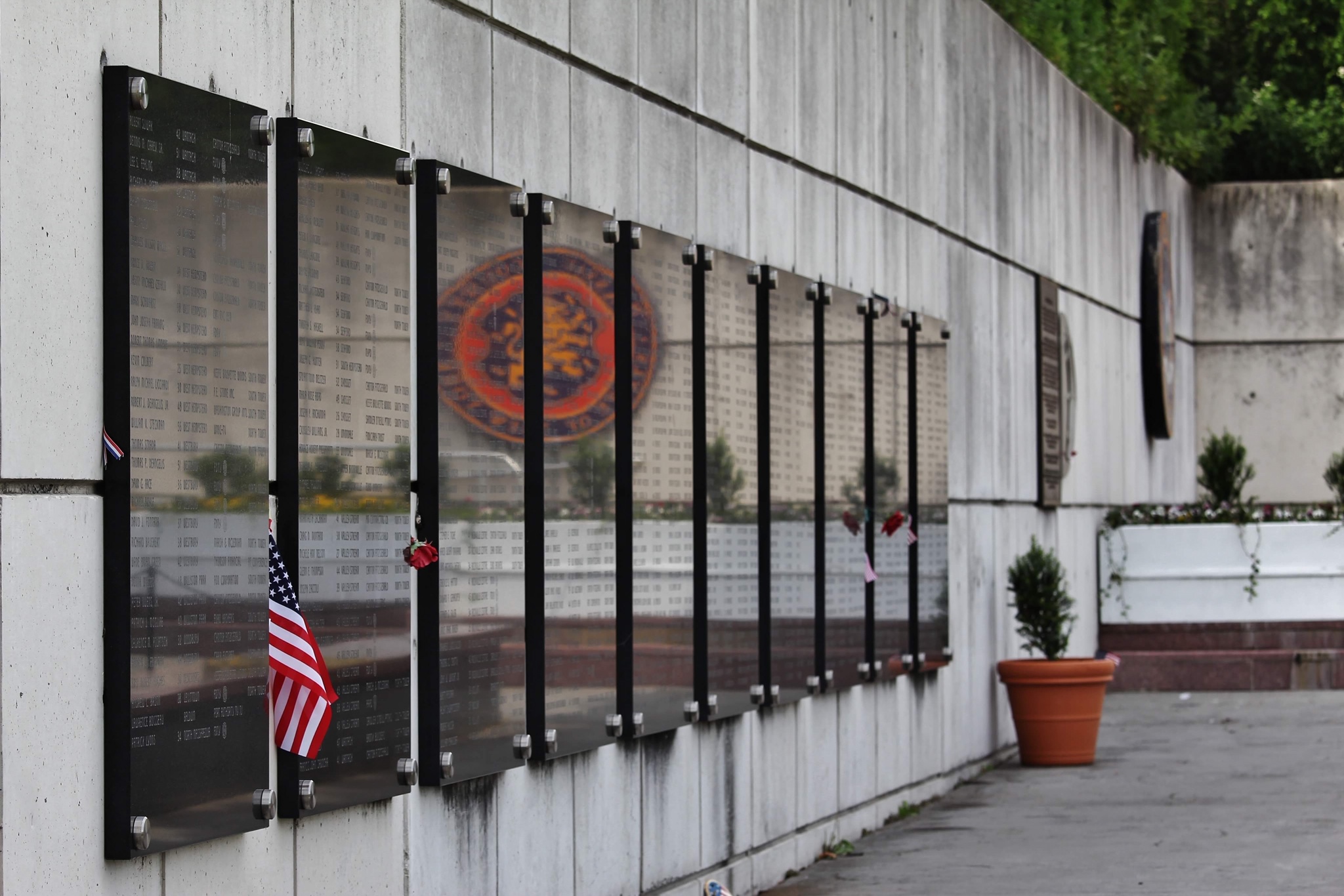 Names inscribed on the memorial wall, with flags and tributes left in remembrance.