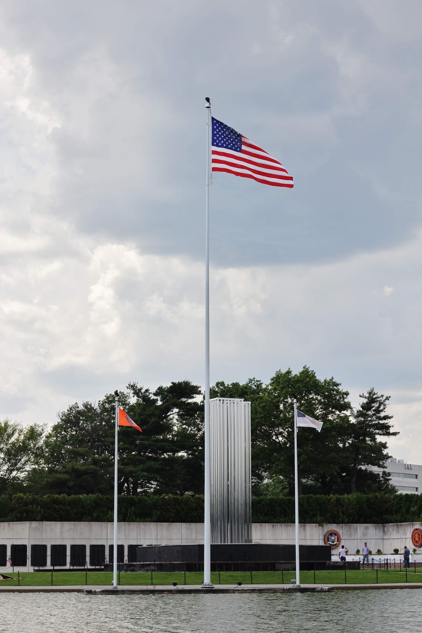 American flag and Nassau County September 11 Memorial towers across the water at Eisenhower Park
